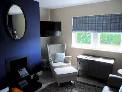 a living room with a chair and a mirror at Beautiful Cottage in Historical Robert Burns Farm - Pass the Keys in Dumfries