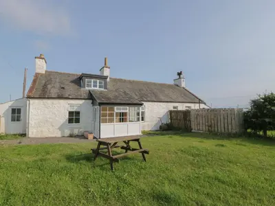 a small house with a picnic table in front of it at Arthur's Cottage in Dumfries