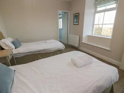 a room with two beds and a window at Arthur's Cottage in Dumfries
