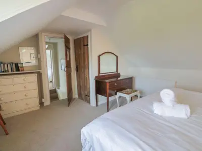 a bedroom with a bed and a dresser and a mirror at Powillimount Cottage in Dumfries