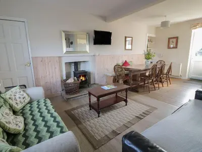 a living room with a table and a fireplace at Powillimount Cottage in Dumfries