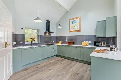 a large kitchen with blue cabinets and a wooden floor at 3 Bed in Loweswater oc-w30224 in Loweswater