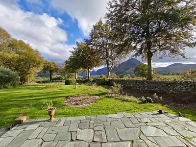 a stone patio with a garden with mountains in the background at 3 Bed in Loweswater oc-w30224 in Loweswater