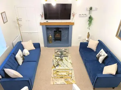 a living room with a blue couch and a fireplace at Beautifully Presented Cosy Town Centre Cottage - Pass the Keys in Dumfries