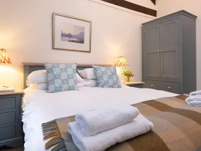a bedroom with a large white bed with blue pillows at Stone Arthur Cottage in Ambleside
