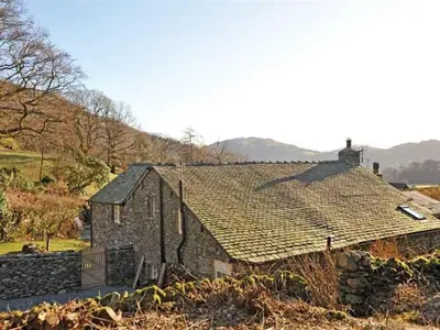 an old stone building with a roof on a field at Stone Arthur Cottage in Ambleside
