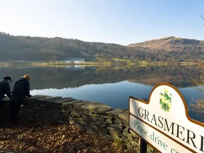 two people standing next to a sign next to a lake at Stone Arthur Cottage in Ambleside