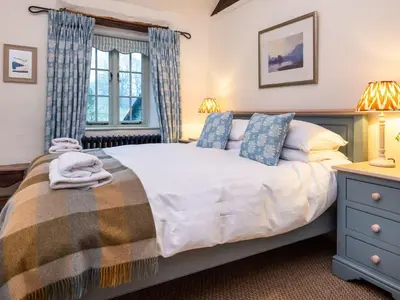 a bedroom with a large bed and two lamps at Stone Arthur Cottage in Ambleside