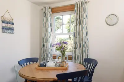 a dining room table with chairs and a window at Shell Cottage in Whithorn