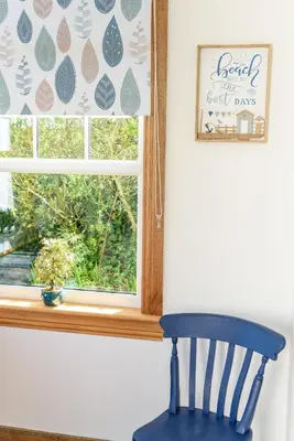 a blue chair sitting in front of a window with a windowpane at Shell Cottage in Whithorn