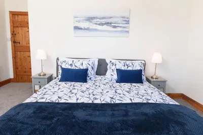 a bedroom with a large bed with blue pillows at Shell Cottage in Whithorn