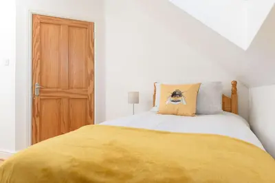 a bedroom with a bed with a yellow blanket on it at Mulberry Cottage in Whithorn
