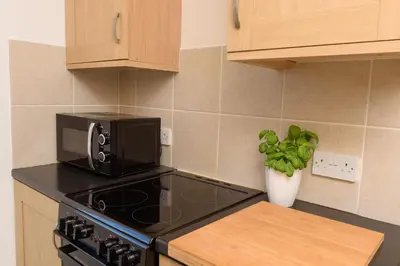 a kitchen with a microwave and a stove top oven at Mulberry Cottage in Whithorn