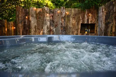 a hot tub filled with water next to a wooden fence at Rowan in Whithorn