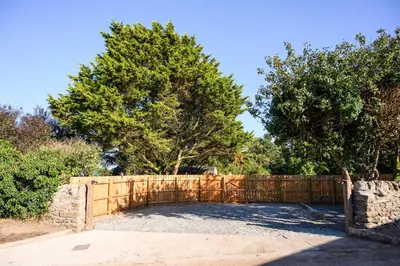 a fence in a yard with trees behind it at Ivy in Whithorn