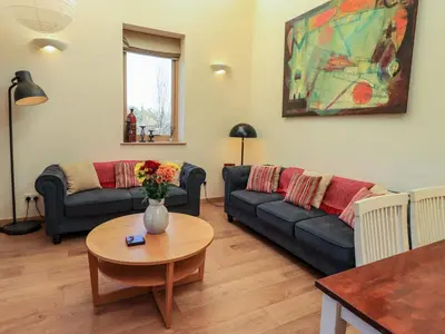 a living room with two couches and a table at Cedrus Lodge in Penrith