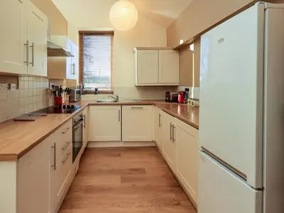 a kitchen with white cabinets and a refrigerator at Cedrus Lodge in Penrith