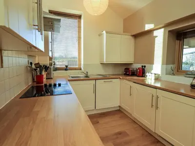 a kitchen with white cabinets and a wooden floor at Cedrus Lodge in Penrith