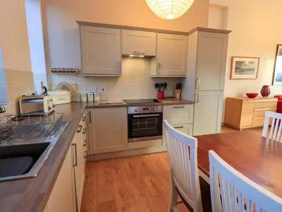 a kitchen with white cabinets and a wooden table at Larch Lodge in Penrith