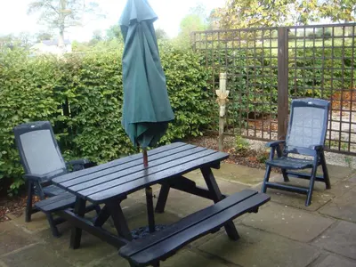a picnic table with an umbrella and two chairs at Barn Owl Cottage in Penrith