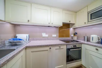 a kitchen with white cabinets and granite counter tops at Ghyll Foot - At the foot of Place Fell, Ullswater in Patterdale