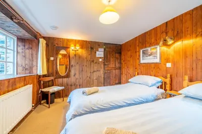 two beds in a room with wooden walls at Ghyll Foot - At the foot of Place Fell, Ullswater in Patterdale