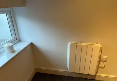 a yellow room with a radiator next to a window at Unique, Large 2 bedroom Flat in Carlisle
