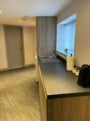 an empty room with a kitchen with a sink at Ground Floor Studio in Longtown