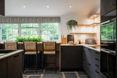 a kitchen with a center island with stools at Grange Bridge Cottage in Grange