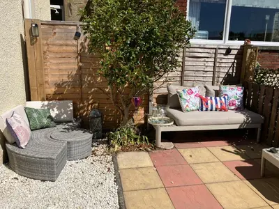 a patio with a couch and a chair and a tree at The Bunker, Golf Cottage in Prestwick