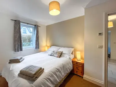 a bedroom with a white bed and a window at Flo's Cottage in Eldrig Village