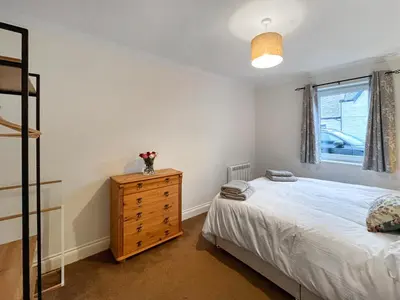 a bedroom with a bed and a dresser and a window at Flo's Cottage in Eldrig Village