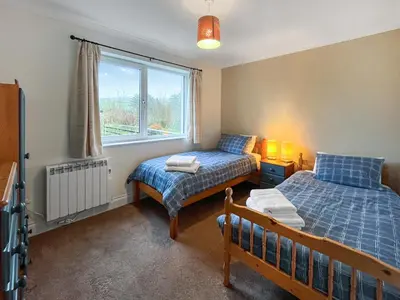 a bedroom with two beds and a window at Flo's Cottage in Eldrig Village