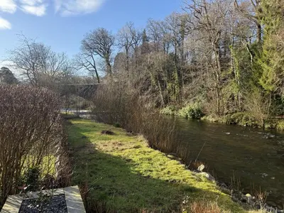 a river with grass and trees next to a river at Greta House in Keswick