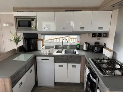 a kitchen with white cabinets and a sink and a stove at The Retreat - Turnberry Holiday Park Amazing Sea View in Girvan