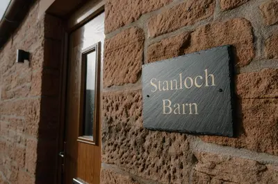 a sign on the side of a brick building at Cosy wee cottage -modern, open plan, parking, EV in Glencaple
