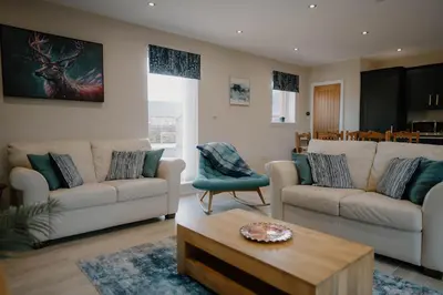 a living room with two couches and a coffee table at Cosy wee cottage -modern, open plan, parking, EV in Glencaple