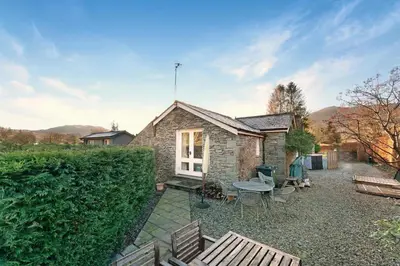 a small stone house with a table and chairs at Rowan Studio Cottage in Grasmere