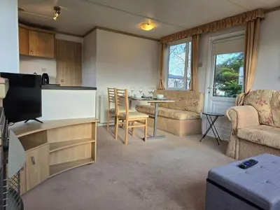 a kitchen and living room with a table and a couch at Elf Wood Lodge - Swimming Spa, Sky Sports, Tennis, Hadrian's Wall listing in Port Carlisle