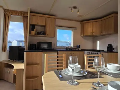a kitchen with a table with two wine glasses on it at Elf Wood Lodge - Swimming Spa, Sky Sports, Tennis, Hadrian's Wall listing in Port Carlisle
