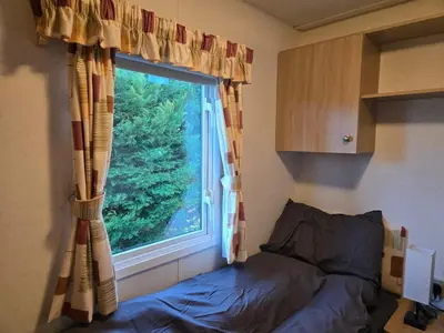 a bedroom with a window and a bed in front of it at Elf Wood Lodge - Swimming Spa, Sky Sports, Tennis, Hadrian's Wall listing in Port Carlisle