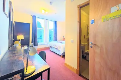 a room with a table and a bed and a bedroom at Fantastic prices for stays of 4 weeks or more - ensuite double rooms -self-catering in Dumfries