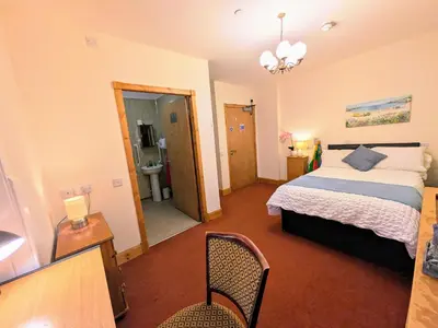 a bedroom with a bed and a table and chair at Fantastic prices for stays of 4 weeks or more - ensuite double rooms -self-catering in Dumfries
