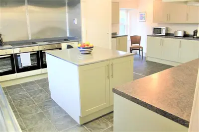a kitchen with white cabinets and a bowl of fruit on a counter at Fantastic prices for stays of 4 weeks or more - ensuite double rooms -self-catering in Dumfries