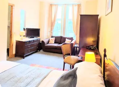 a room with a bed and a couch and a television at Fantastic prices for stays of 4 weeks or more - ensuite double rooms -self-catering in Dumfries
