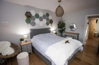 a bedroom with a white bed with a hexagonal wall at Hidden Hive in Gretna