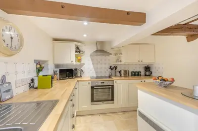 a kitchen with white cabinets and a clock on the wall at 2 Bed in Greystoke oc-s30412 in Greystoke