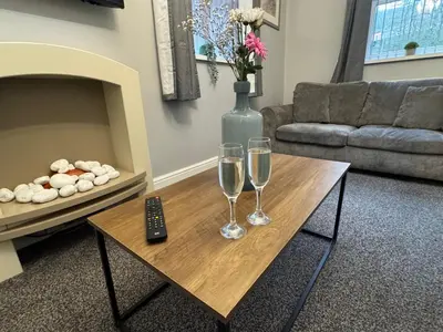 a living room with two wine glasses and a remote control at Omega Apartment - 3 Bedrooms - Sleeps 5 in Whitehaven