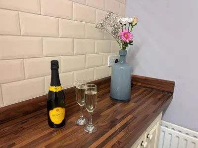 a counter with two glasses of wine and a vase with flowers at Omega Apartment - 3 Bedrooms - Sleeps 5 in Whitehaven