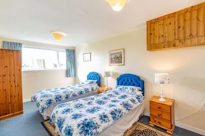 two beds in a room with blue chairs at Dunrod - Overlooking the bay in Kirkcudbright